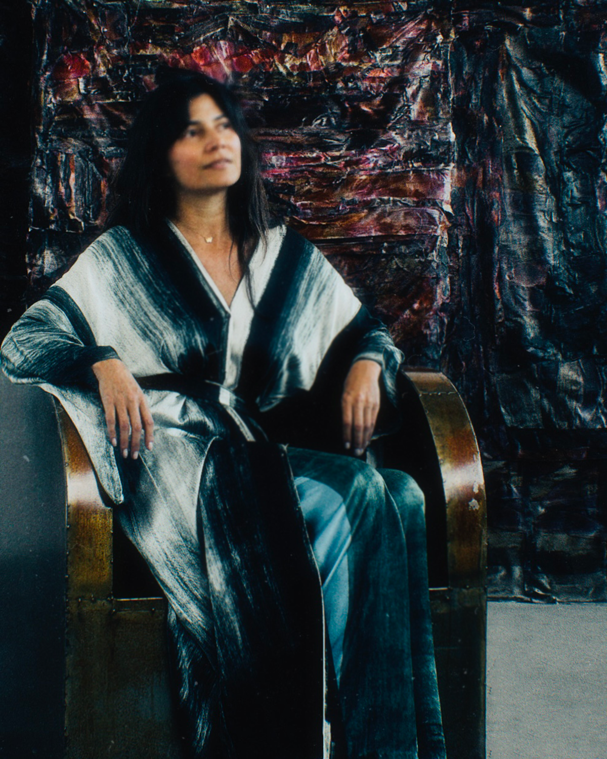 Carmen Molina, founder of CARMEN, captured in a self-portrait at her studio. Behind her one of her art pieces, a silk-collage using encaustic wax medium.